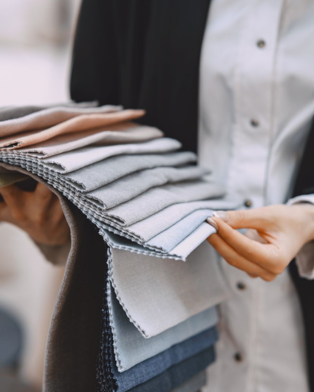 Fabric supplier holding multiple knit fabric swatches showing color and texture options