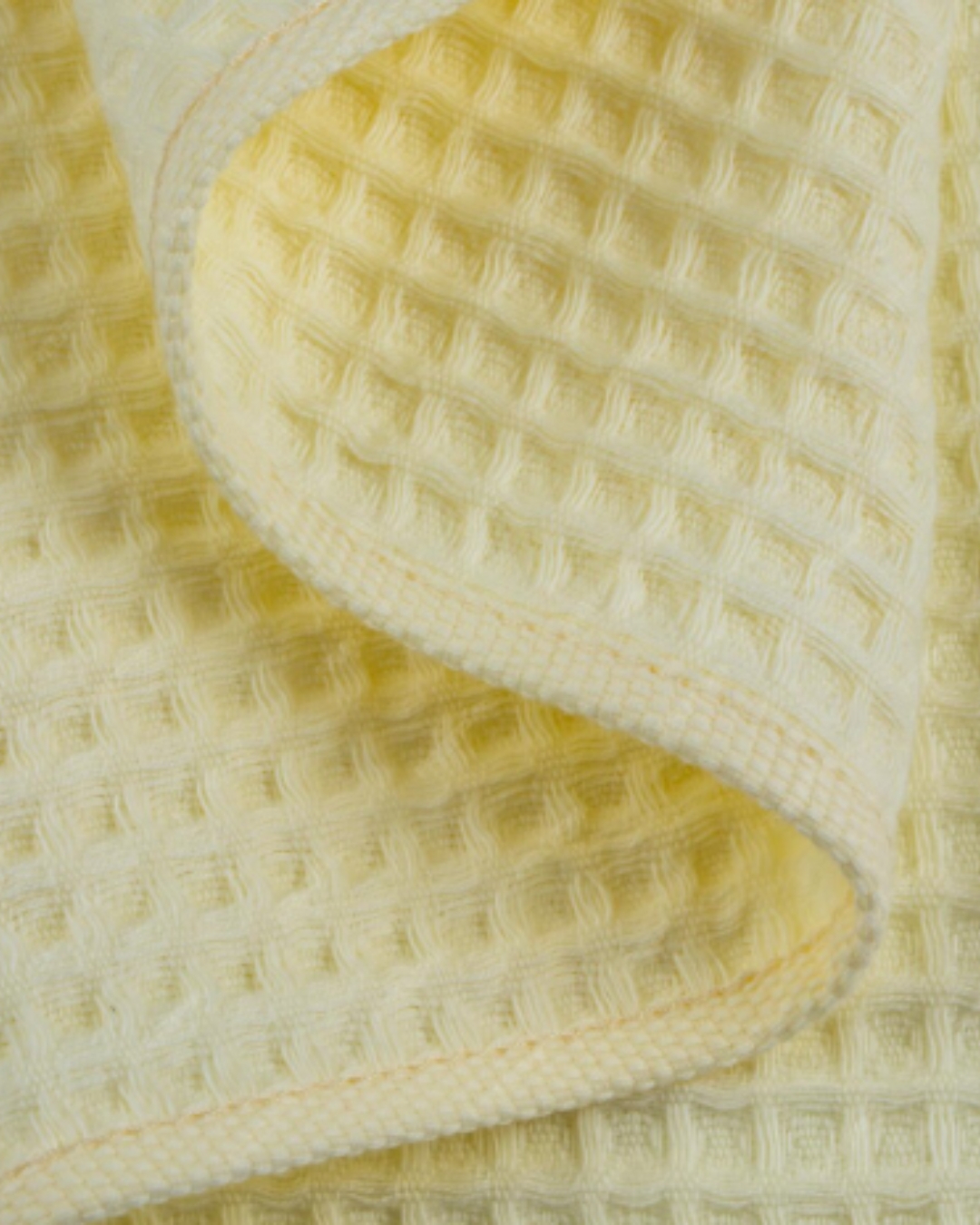 Close-up of yellow waffle fabric texture showing soft breathable cotton pattern